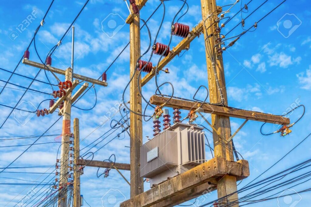 electricity supply system for users, high-voltage power transformers mounted on wooden poles on a blue sky background